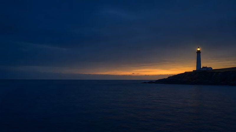 A lighthouse seen from open water at first light